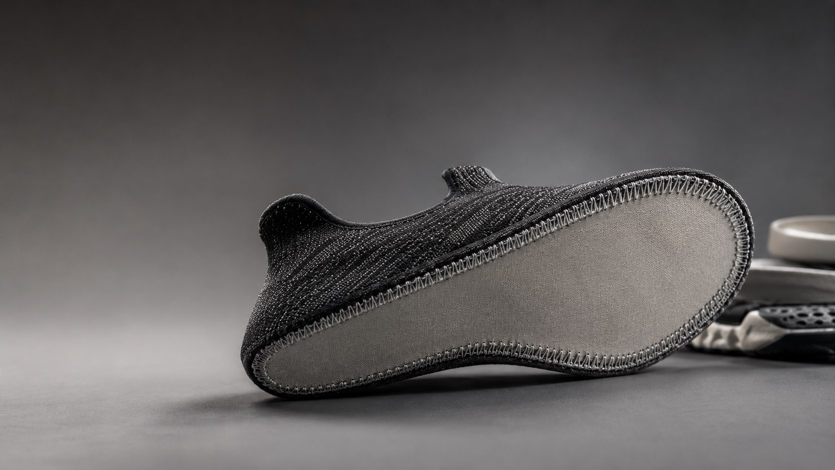 Close-up of a knitted shoe upper Strobel-stitched to its board, showing the stitching around the perimeter